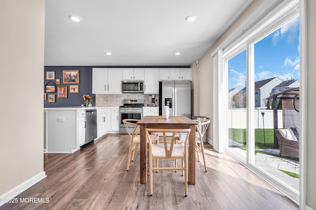 dining area with wood finished floors, a wealth of natural light, and recessed lighting