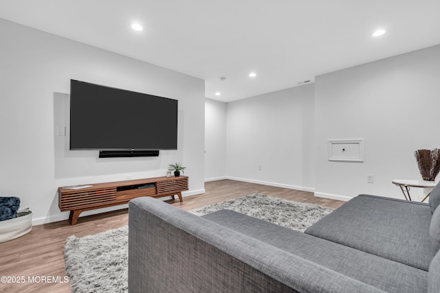living area with baseboards, wood finished floors, and recessed lighting