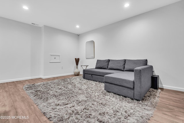 living area with wood finished floors, visible vents, and baseboards