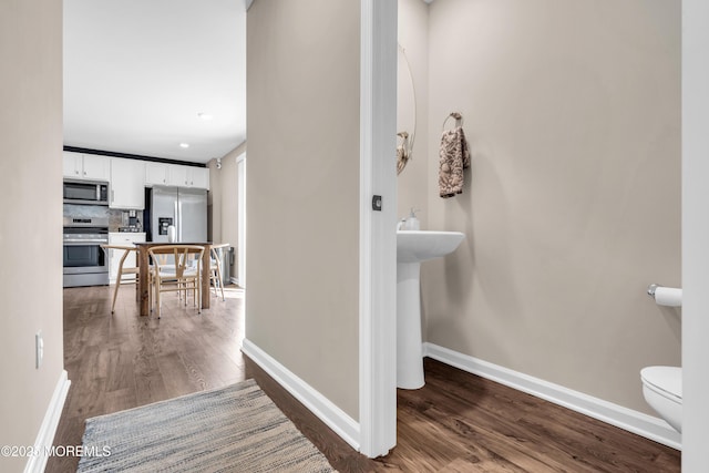 interior space with decorative backsplash, baseboards, and wood finished floors