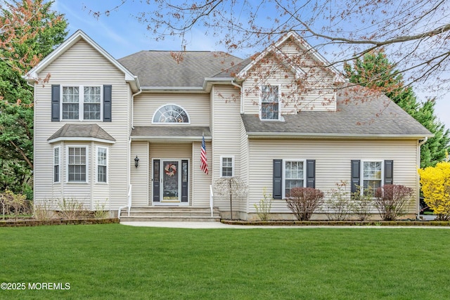 traditional-style house featuring roof with shingles and a front lawn