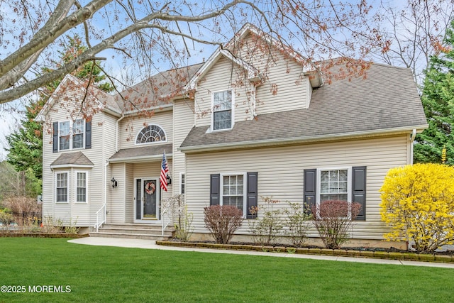 traditional-style home featuring a shingled roof and a front lawn
