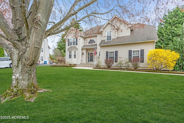traditional-style house featuring a front yard and roof with shingles