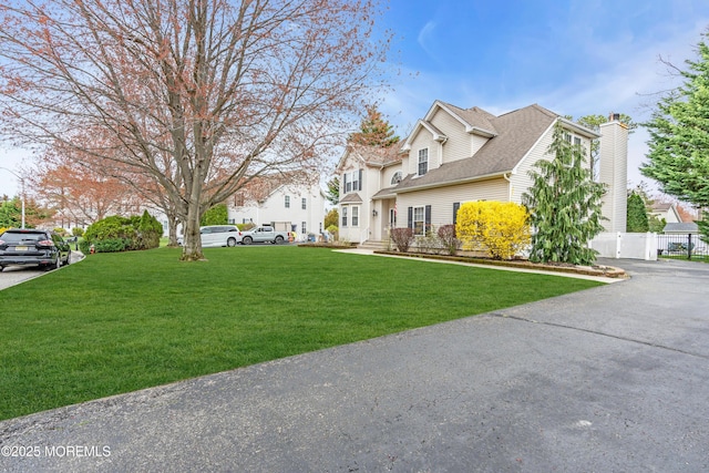 view of property exterior with a chimney, a residential view, fence, and a lawn