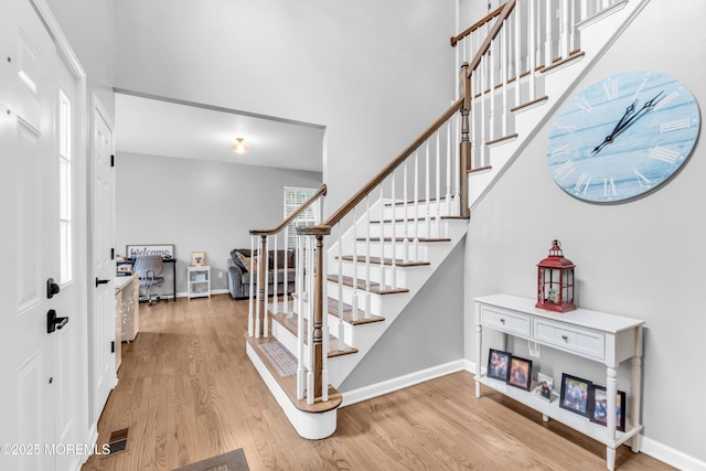 entrance foyer featuring light wood-style flooring, baseboards, and stairs