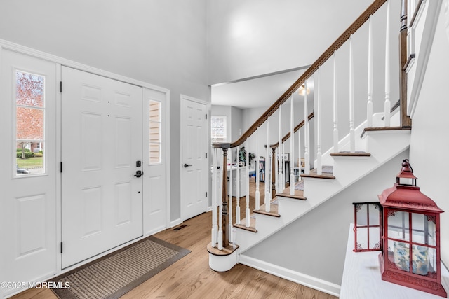foyer with a healthy amount of sunlight, stairway, and wood finished floors