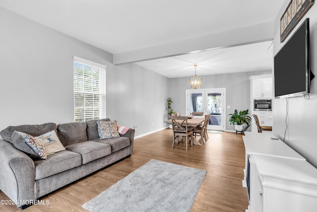 living room featuring light wood-style flooring, an inviting chandelier, and baseboards