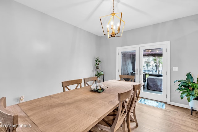 dining area with french doors, wood finished floors, a notable chandelier, and baseboards