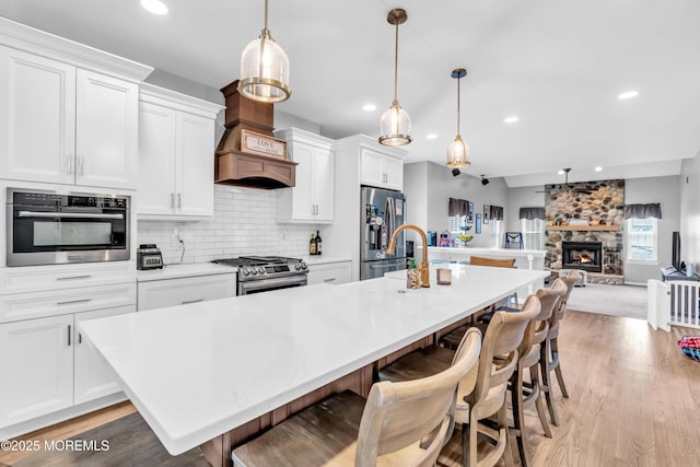 kitchen with a kitchen island with sink, recessed lighting, light wood finished floors, and appliances with stainless steel finishes
