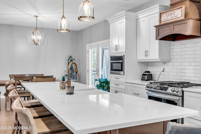 kitchen featuring a large island with sink, tasteful backsplash, white cabinets, stainless steel appliances, and premium range hood
