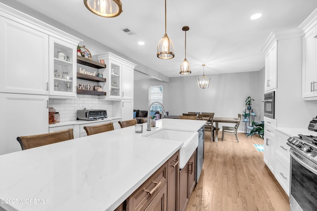 kitchen featuring visible vents, open shelves, a sink, white cabinetry, and stainless steel appliances