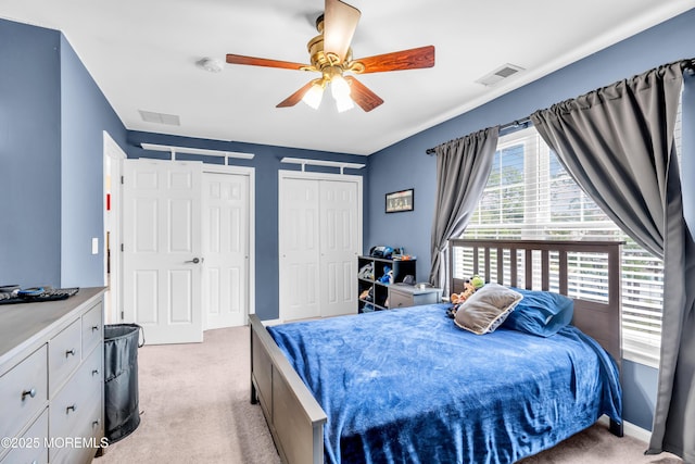 bedroom with visible vents, multiple closets, and light colored carpet