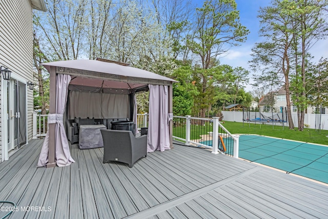 deck featuring a trampoline, a fenced backyard, a gazebo, and a lawn
