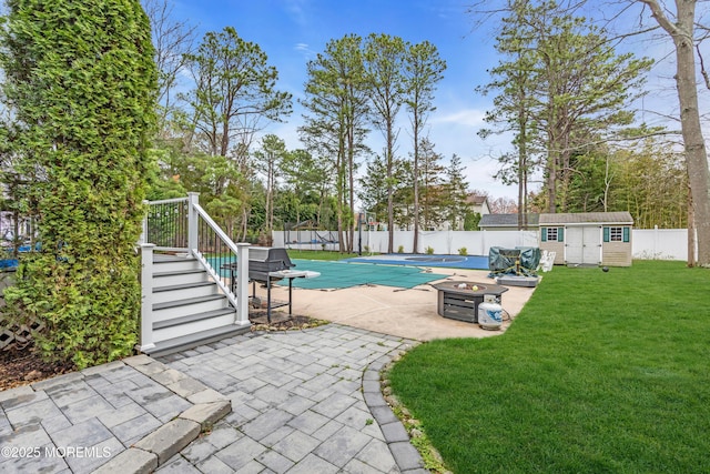 view of swimming pool featuring a fenced in pool, a patio, an outdoor structure, a fenced backyard, and a lawn