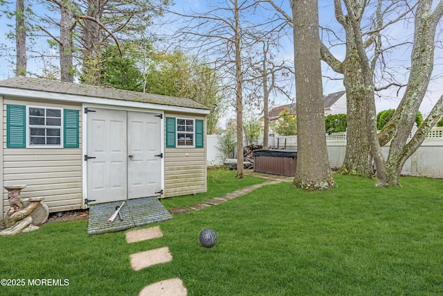 view of shed with a fenced backyard and a hot tub