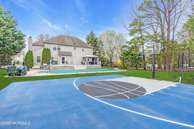 view of sport court with a trampoline, a fenced in pool, basketball court, a yard, and fence