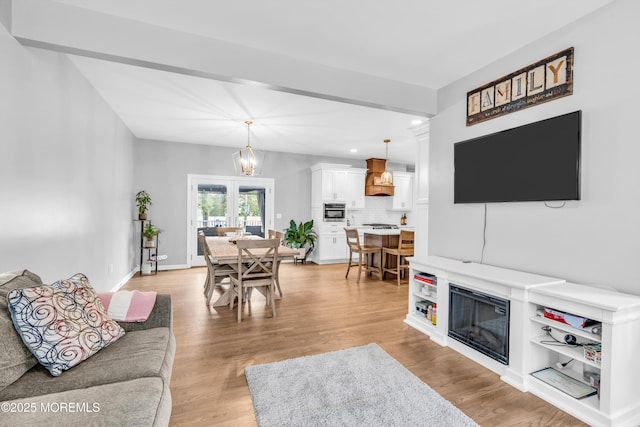 living area featuring a chandelier, light wood finished floors, a glass covered fireplace, and recessed lighting