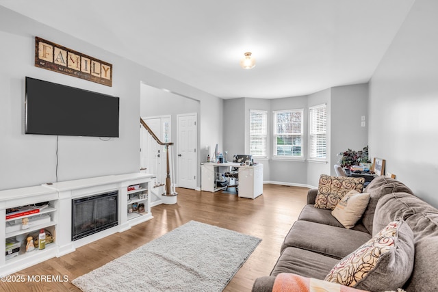 living area featuring baseboards, stairway, and wood finished floors