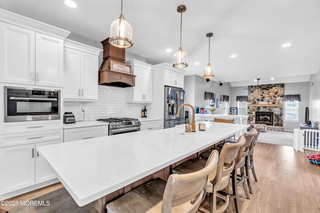 kitchen with light wood-style flooring, recessed lighting, a center island with sink, and stainless steel appliances