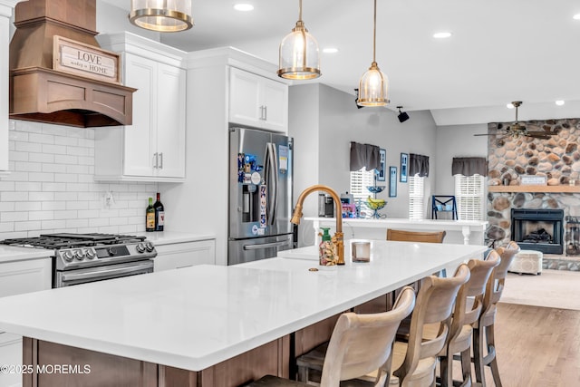 kitchen with open floor plan, a ceiling fan, backsplash, a center island with sink, and stainless steel appliances