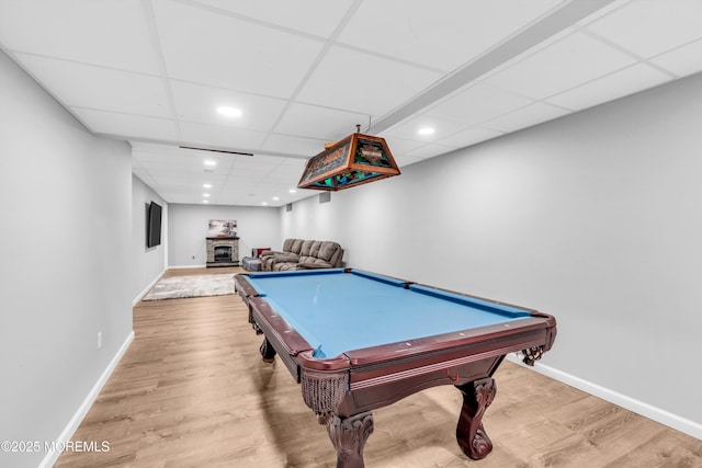 game room with baseboards, a paneled ceiling, and wood finished floors
