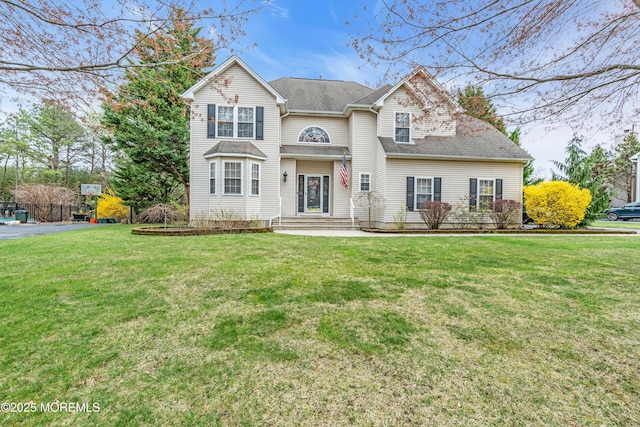 traditional-style home featuring a front yard and a shingled roof