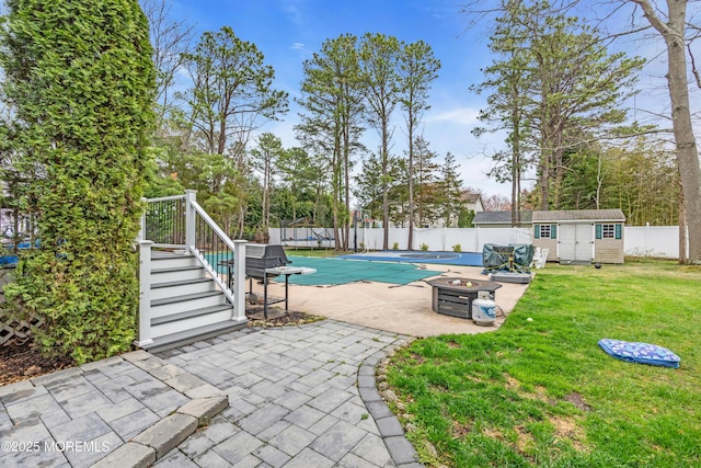 view of pool featuring a fenced in pool, a patio, a fenced backyard, an outbuilding, and a lawn