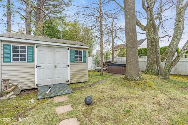 view of shed with a fenced backyard and a hot tub
