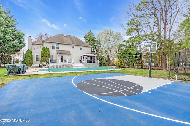 view of basketball court with a trampoline, a swimming pool, basketball court, and fence