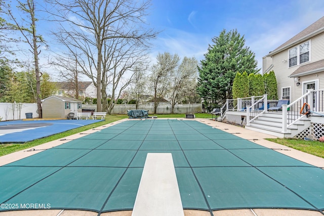 view of swimming pool featuring an outbuilding, a wooden deck, and a fenced backyard