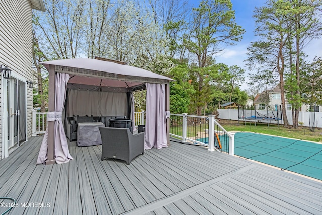 deck with a trampoline, a fenced backyard, and a gazebo