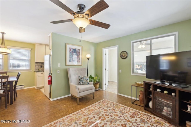 living room with wood finished floors, a ceiling fan, and baseboards