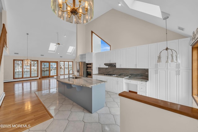 3166 Windsor Ave, Toms River, NJ 08753 - kitchen featuring an inviting chandelier, high vaulted ceiling, a sink, appliances with stainless steel finishes, and a skylight
