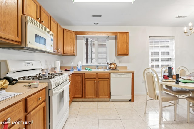 kitchen featuring white appliances, light countertops, a sink, and brown cabinets