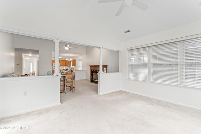 unfurnished living room with light carpet, a fireplace with flush hearth, ceiling fan with notable chandelier, and baseboards