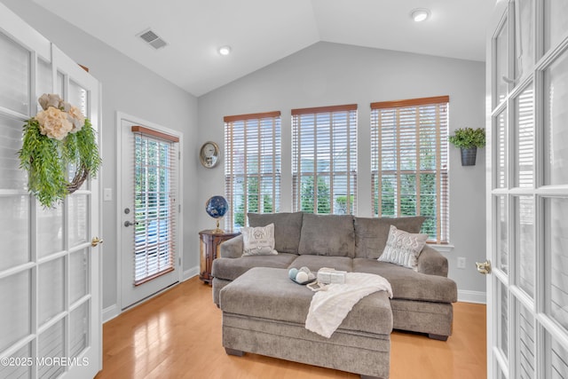 living room featuring visible vents, baseboards, light wood-type flooring, and lofted ceiling