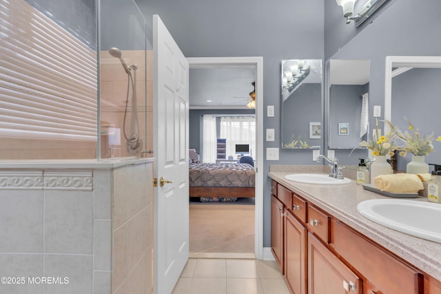 ensuite bathroom with tile patterned floors, ensuite bathroom, tiled shower, ceiling fan, and a sink