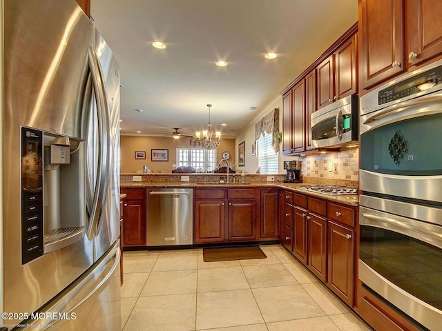 kitchen featuring a peninsula, an inviting chandelier, stone counters, and stainless steel appliances