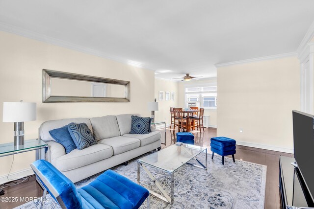 living area with ornamental molding, ceiling fan, wood finished floors, and baseboards
