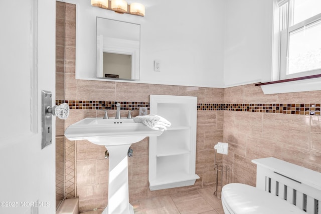 bathroom with toilet, tile patterned floors, and tile walls