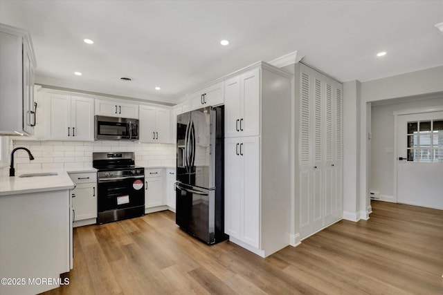 kitchen with tasteful backsplash, light countertops, light wood-style floors, stainless steel appliances, and a sink