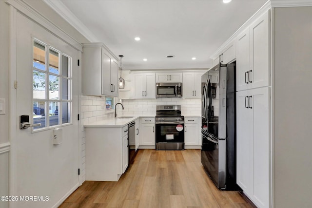 kitchen with light wood-style floors, tasteful backsplash, appliances with stainless steel finishes, light countertops, and a sink
