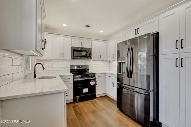 kitchen with visible vents, a sink, appliances with stainless steel finishes, white cabinetry, and light stone counters