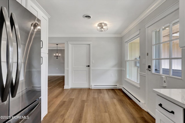 interior space featuring a baseboard radiator, light wood finished floors, visible vents, and a wealth of natural light