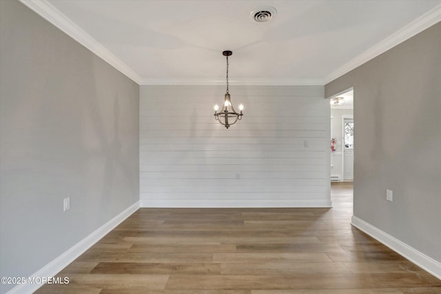 unfurnished dining area featuring a chandelier, wood finished floors, baseboards, and ornamental molding