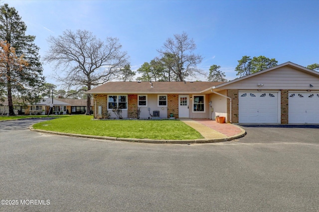 ranch-style home featuring brick siding, an attached garage, driveway, and a front lawn