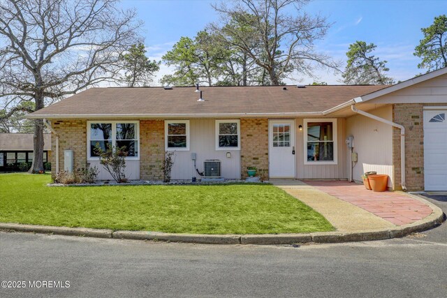 ranch-style house with a front yard, brick siding, and central AC