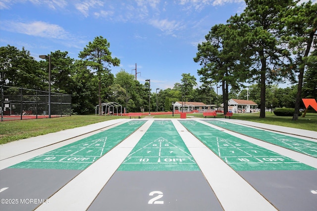 view of community with a yard, shuffleboard, and fence