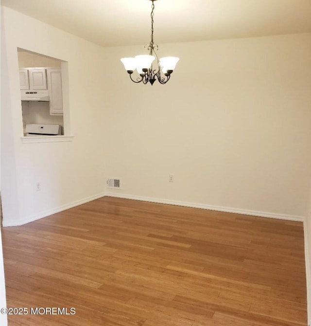 96 Drew Ct, Manalapan, NJ 07726 - empty room featuring visible vents, baseboards, light wood finished floors, and a notable chandelier
