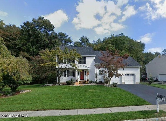 colonial home featuring a front lawn and aphalt driveway